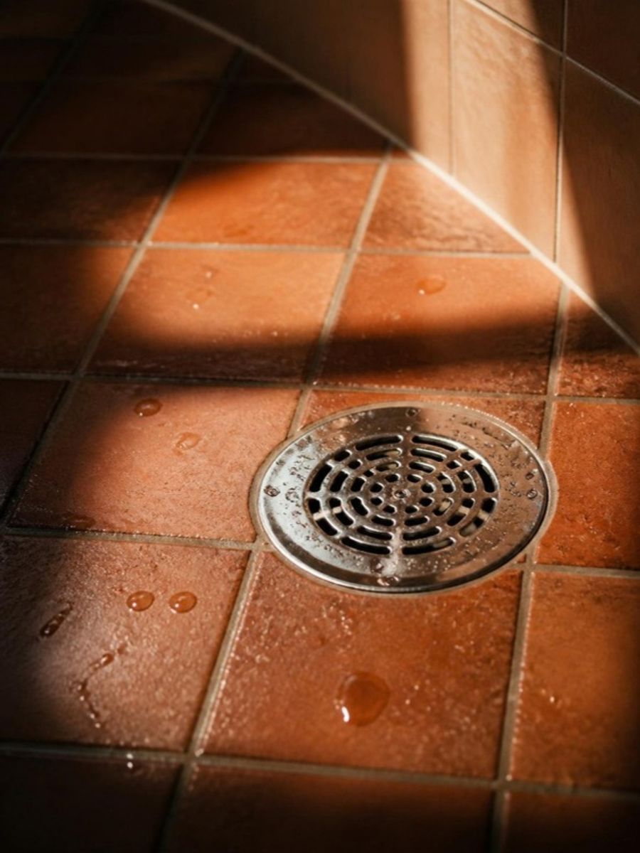 Ralo de inox limpo no piso de cerâmica, com luz de fim de tarde