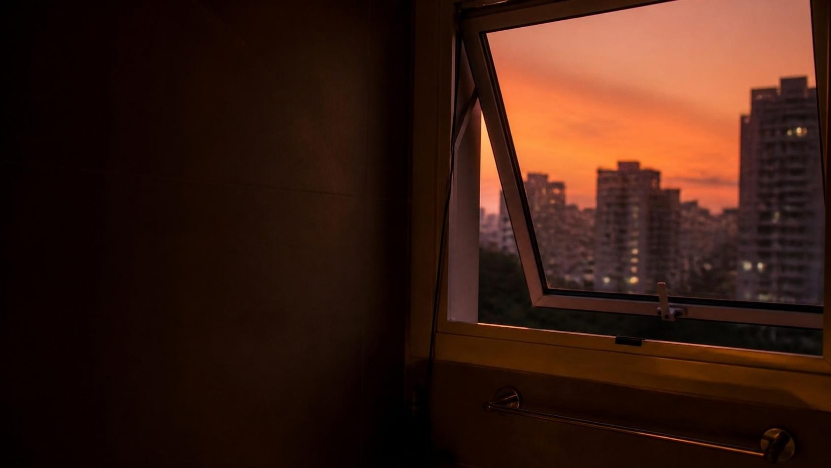 Janela do banheiro aberta para os prédios de Belo Horizonte ao entardecer